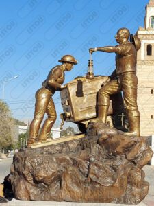 Sculpture de mineurs poussant une charrette, hommage à leur travail et leur engagement.